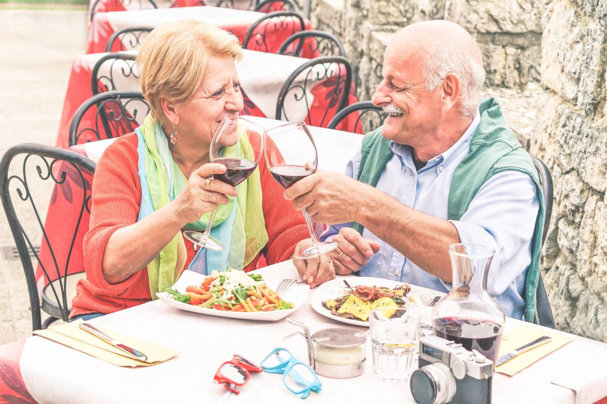 Older couple enjoy a meal with wine budget senior travel