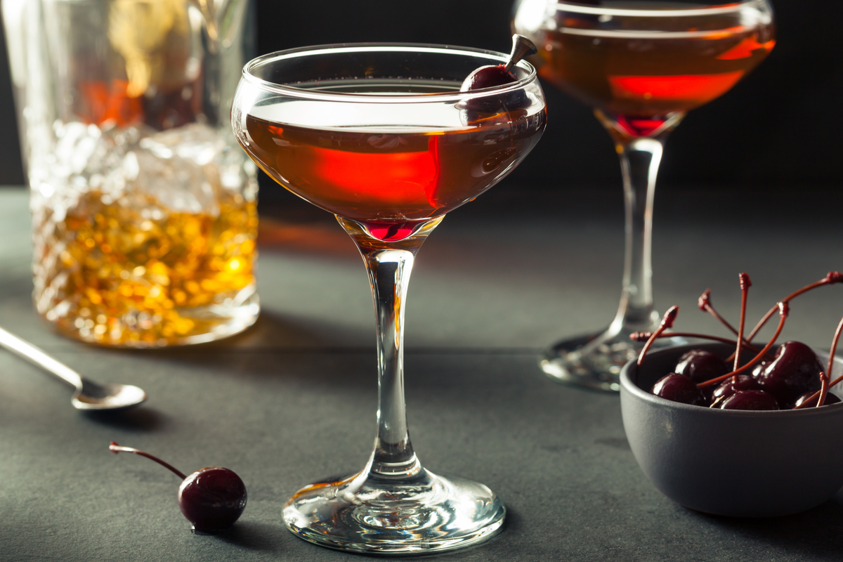 Two manhattan cocktails garnished with maraschino cherries
